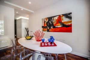 a white dining room table with chairs and a painting at Pgrhome Luxury Apartments Riverside in Rome