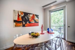 una sala da pranzo con tavolo e sedie bianchi di Pgrhome Luxury Apartments Riverside a Roma
