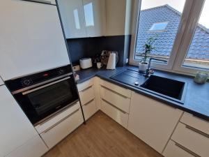 eine Küche mit einem Kühlschrank, einer Spüle und einem Fenster in der Unterkunft Apartment nahe Meyer Werft in Ostfriesland mit Küche & Netflix in Westoverledingen