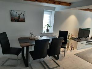 a dining room with a table and chairs and a television at Ferienwohnung Alte Glaserei in Ilsenburg