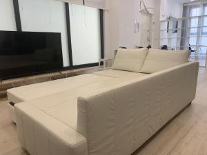 un sofá blanco en una habitación con TV de pantalla plana en MonKeys Apartments Pagés del Corro Triana, en Sevilla