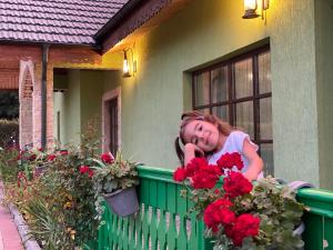 Ein junges Mädchen, das auf einem Zaun mit roten Blumen lehnt. in der Unterkunft Agropensiunea Valea Fagilor in Luncaviţa