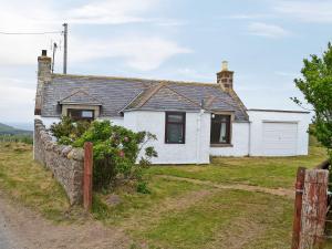 ein weißes Haus mit einem Zaun davor in der Unterkunft Mains Of Auchmedden Cottage in Pennan