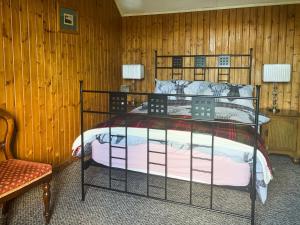 1 dormitorio con 1 cama en una pared de madera en Mains Of Auchmedden Cottage, en Pennan