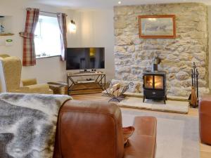 a living room with a stone wall and a fireplace at Broats Barn in Ingleton