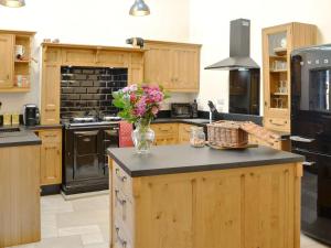 a kitchen with wooden cabinets and a vase of flowers on a counter at Broats Barn in Ingleton