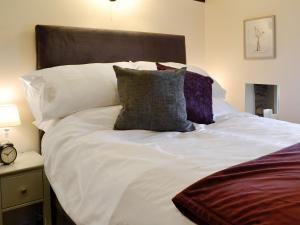 a large bed with white sheets and pillows at Broats Barn in Ingleton