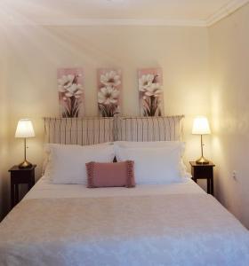 een bed met witte kussens en bloemen aan de muur bij Lorantina House_ Holidays in Corfu in Spartýlas