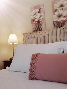 a bedroom with a white bed with a pink pillow at Lorantina House_ Holidays in Corfu in Spartýlas