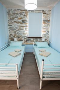 2 Betten in einem Zimmer mit Ziegelwand in der Unterkunft Με θέα το ηλιοβασιλεμα 2 in Áfissos