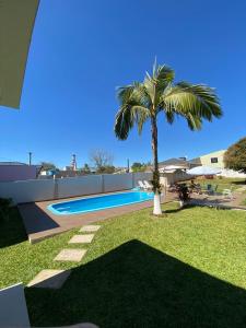 a palm tree in a yard with a swimming pool at Pousada São Gabriel in Ametista do Sul