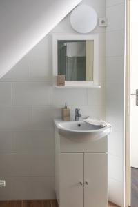 een witte badkamer met een wastafel en een spiegel bij Hauptman apartman in Nagyatád