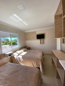 a bedroom with two beds and a flat screen tv at Pousada São Gabriel in Ametista do Sul
