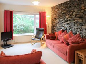 a living room with red furniture and a stone wall at Cobble Rigg in Threlkeld
