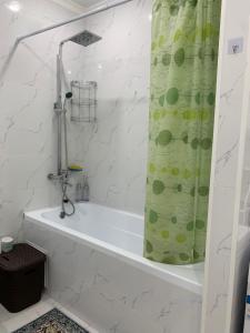 a bath tub with a shower curtain in a bathroom at Апартаменты на Назарбаева in Almaty