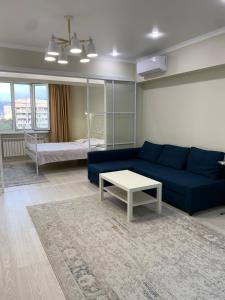 sala de estar con sofá azul y mesa en Апартаменты на Назарбаева en Almaty