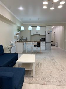 a living room and kitchen with a blue couch and a table at Апартаменты на Назарбаева in Almaty