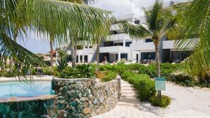 a resort with a swimming pool and palm trees at The Reef 28 Blue Bay Curacao in Dorp Sint Michiel