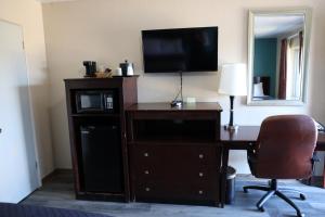 um quarto de hotel com uma secretária, uma televisão e um computador em Budget Inn em Alamogordo