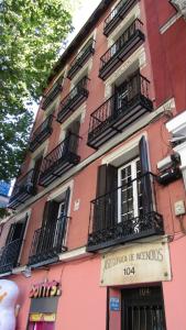 un edificio rosa con balcones y una señal en él en Pensión Mollo, en Madrid