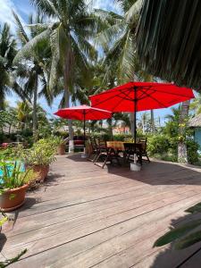 a wooden deck with tables and red umbrellas at Hotel Atelie del Mar in Monterrico