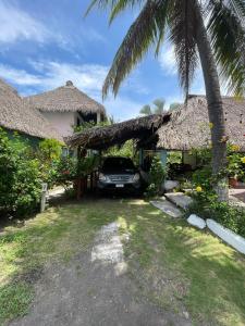 a car parked in front of a house with a palm tree at Hotel Atelie del Mar in Monterrico