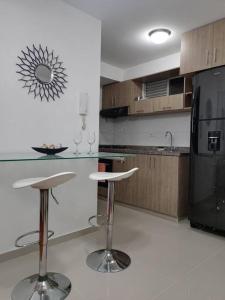 Los Patios的住宿－Hermoso apartamento con zona social，厨房配有2把吧台凳和1台黑冰箱