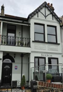 a white building with a balcony and a sunoco store at Suenos Guesthouse in Southend-on-Sea