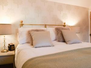 Una cama con sábanas blancas y almohadas en un dormitorio en Clickers Cottage, en Woodford