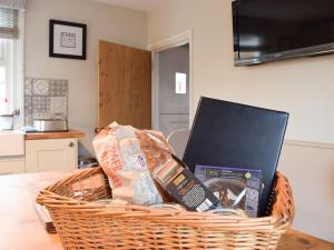 a basket filled with books and a laptop on a table at Clickers Cottage in Woodford