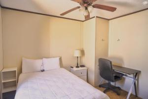 a bedroom with a bed and a desk and a ceiling fan at Ellipse Global Lodge in Carlsbad