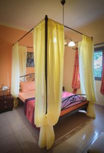 a bedroom with a canopy bed with yellow curtains at Vretti's House in Kythira