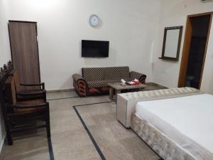 Habitación con cama, sofá y TV. en Hotel Day IN One, en Lahore