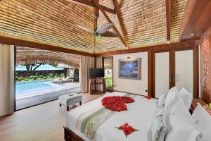 a bedroom with a large bed with red flowers on it at Le Taha'a by Pearl Resorts in Motu Tautau
