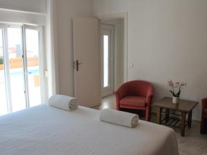 a bedroom with a white bed and a red chair at Casa Azul in Praia da Areia Branca