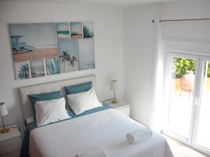 a white bedroom with a bed and a window at Casa Azul in Praia da Areia Branca