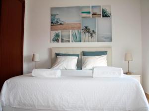 プライア・ダ・アレイア・ブランカにあるCasa Azulの白いベッド1台、壁に4枚の写真が飾られたベッドルーム1室
