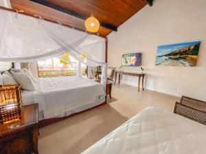 a bedroom with two beds and a table and a window at Arraial Bangalô Praia Hotel in Arraial d'Ajuda