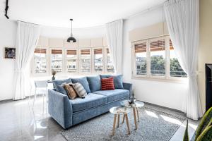 a living room with a blue couch and windows at HA MESILLA - Modern Collection - By HOMY in Tel Aviv