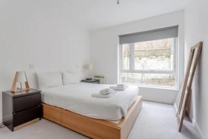 a white bedroom with a bed and a window at Spacious 1 Bed apartment near Shoreditch Park in London