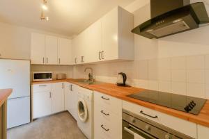 a kitchen with white cabinets and a washer at Spacious 1 Bed apartment near Shoreditch Park in London