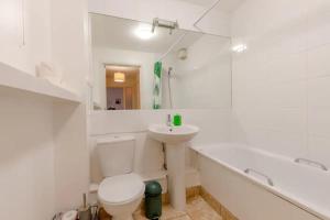 a white bathroom with a sink and a toilet and a tub at Spacious 1 Bed apartment near Shoreditch Park in London