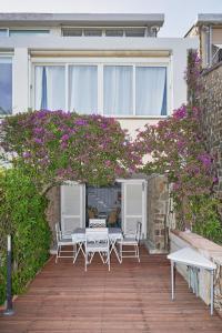 una mesa y sillas en un patio con flores púrpuras en Cottage Punta Ala Residential Area with Pool, en Punta Ala