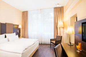 a hotel room with a bed and a desk and a bed at Villa Hotel Frankfurt by MZ HotelCollection in Frankfurt