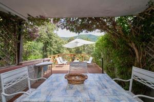 a patio with a table and chairs and an umbrella at Cottage Punta Ala Residential Area with Pool in Punta Ala