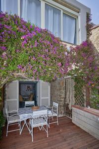 una mesa y sillas en una terraza con flores púrpuras en Cottage Punta Ala Residential Area with Pool, en Punta Ala