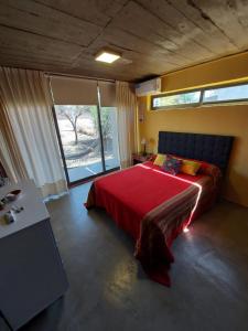 een slaapkamer met een bed met een rode deken en een raam bij SARA HOUSE LARGE in Santa Rosa de Calamuchita