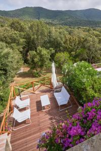 a wooden deck with white chairs and flowers at Cottage Punta Ala Residential Area with Pool in Punta Ala