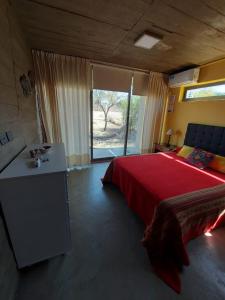 sypialnia z dużym czerwonym łóżkiem i oknem w obiekcie SARA HOUSE LARGE w mieście Santa Rosa de Calamuchita