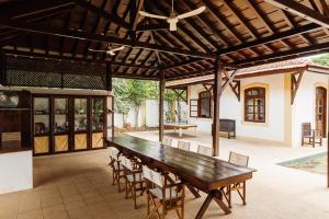 een patio met een houten tafel en stoelen bij Roça Vale dos Prazeres in São Tomé